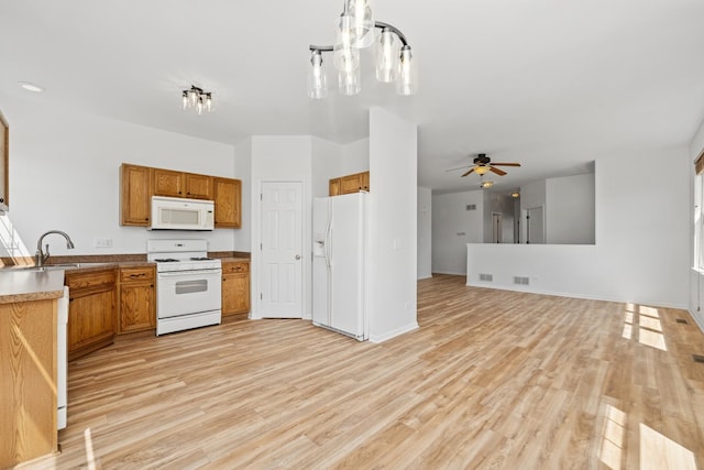 kitchen featuring a sink, light wood finished floors, white appliances, a ceiling fan, and brown cabinetry