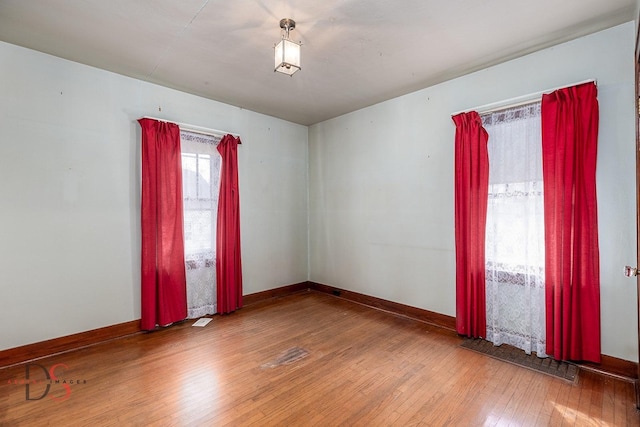 empty room with baseboards, visible vents, and hardwood / wood-style floors