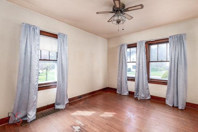 unfurnished room with baseboards, ceiling fan, wood finished floors, and visible vents