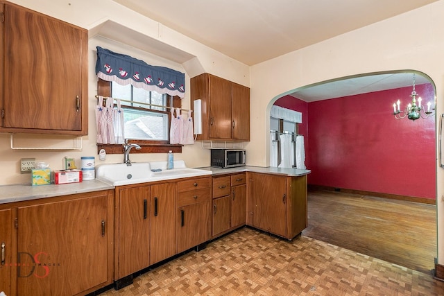 kitchen featuring stainless steel microwave, brown cabinetry, and a sink