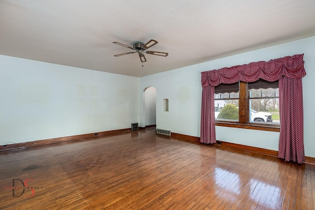 unfurnished living room with visible vents, a ceiling fan, baseboards, hardwood / wood-style flooring, and arched walkways