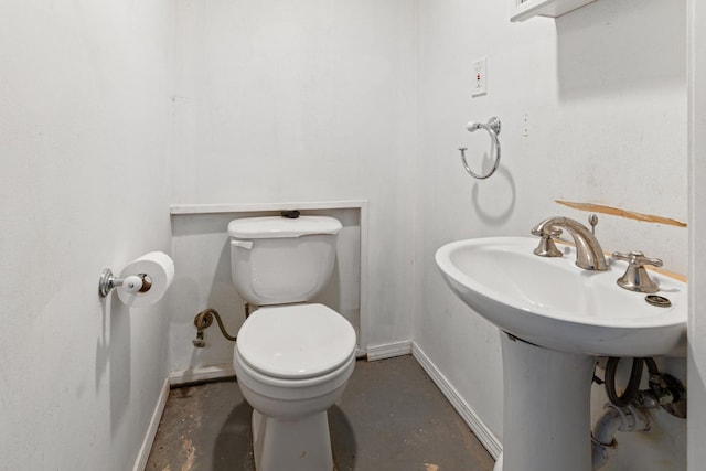 bathroom with baseboards, toilet, and concrete flooring