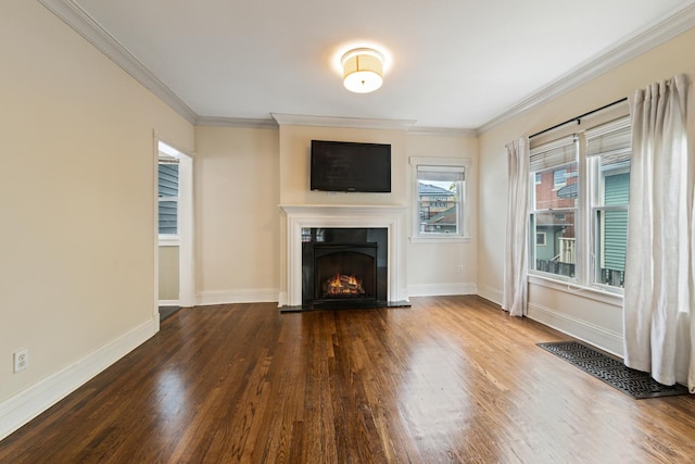 unfurnished living room with wood finished floors, a lit fireplace, baseboards, and ornamental molding