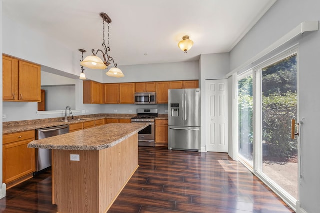 1844 Candlelight Cir, Montgomery, IL 60538 - kitchen with appliances with stainless steel finishes, a center island, dark wood finished floors, brown cabinetry, and hanging light fixtures