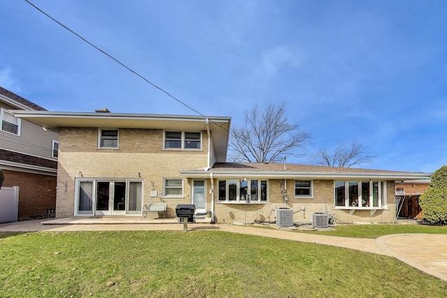 back of property featuring a patio area, a lawn, brick siding, and central AC