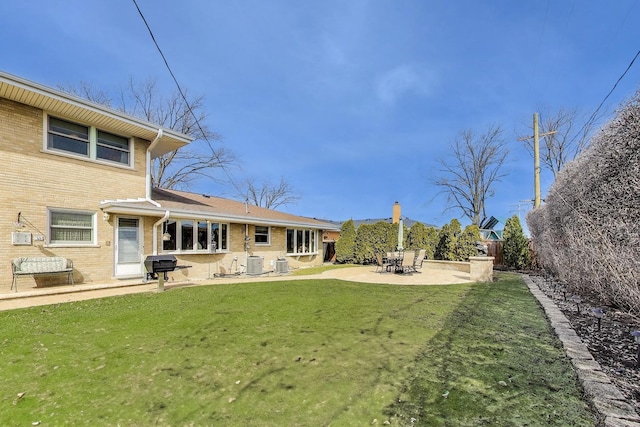 rear view of house with a fenced backyard, central air condition unit, brick siding, a patio area, and a lawn