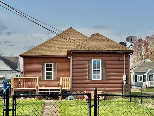 rear view of house with fence, a lawn, a shingled roof, and a deck