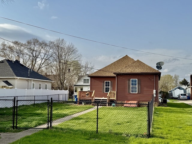 rear view of house with a gate, a lawn, a shingled roof, fence private yard, and a wooden deck