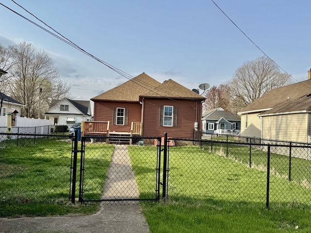back of property featuring a gate, fence, a yard, and a shingled roof