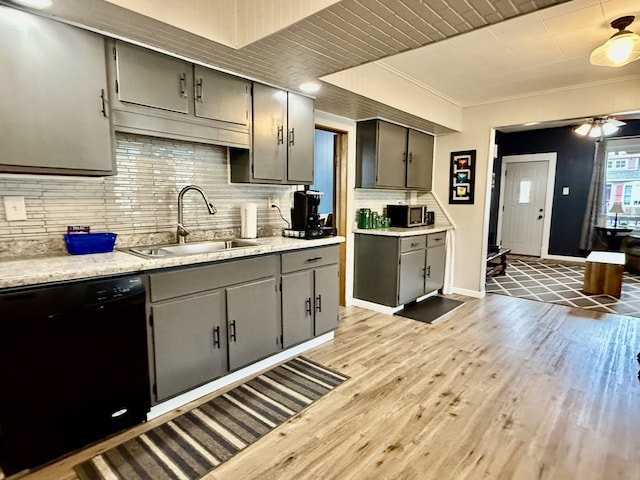 kitchen featuring a sink, light wood-style floors, dishwasher, light countertops, and backsplash