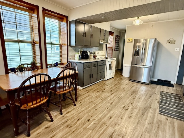 kitchen featuring light wood finished floors, under cabinet range hood, ornamental molding, stainless steel fridge, and electric range