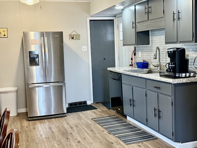 kitchen with light wood finished floors, a sink, gray cabinetry, black dishwasher, and stainless steel fridge