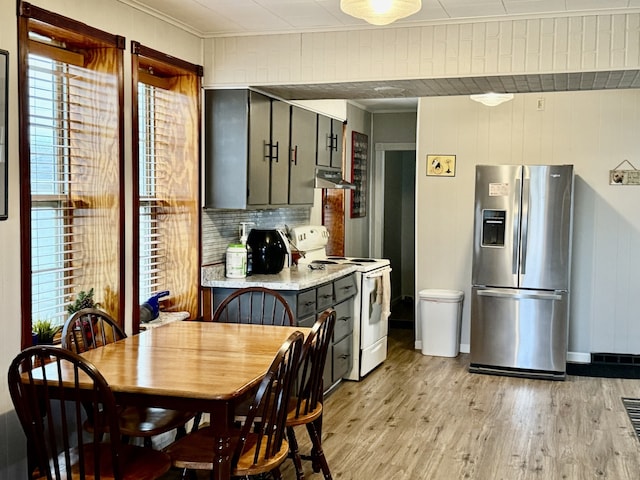 kitchen with electric range, extractor fan, stainless steel refrigerator with ice dispenser, and a wealth of natural light