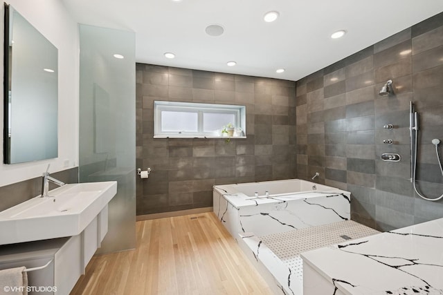 full bathroom featuring a garden tub, wood finished floors, tile walls, a walk in shower, and recessed lighting