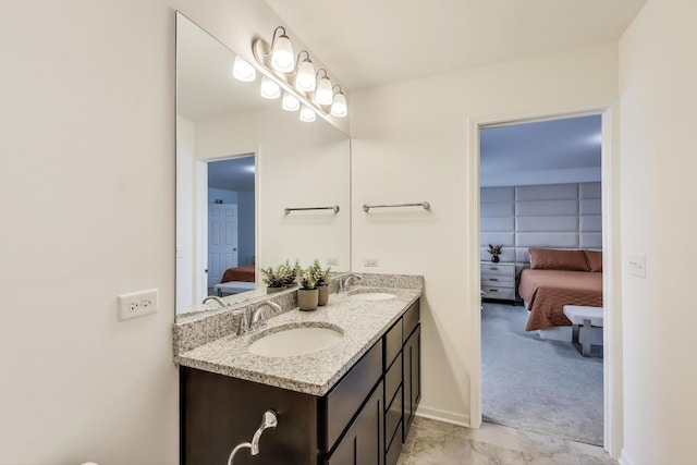 bathroom with double vanity, ensuite bath, baseboards, and a sink