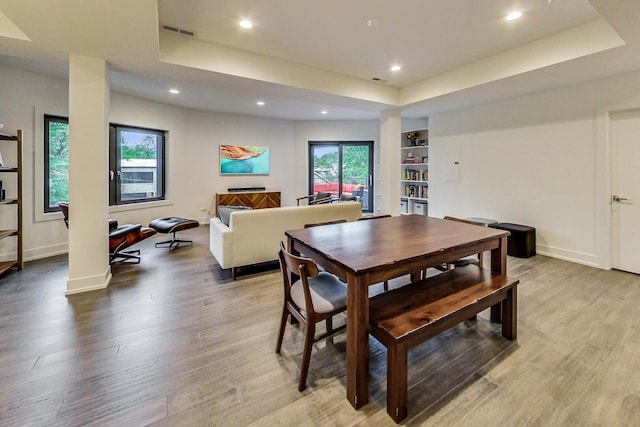 dining area featuring baseboards, a tray ceiling, wood finished floors, and visible vents