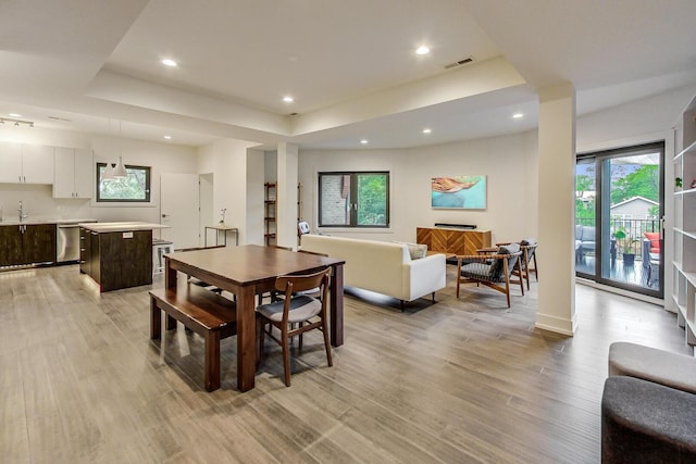 dining area featuring a tray ceiling, light wood-style floors, visible vents, and recessed lighting