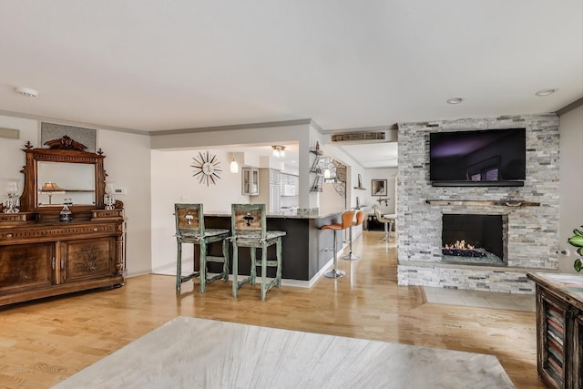living room featuring a stone fireplace, baseboards, and wood finished floors