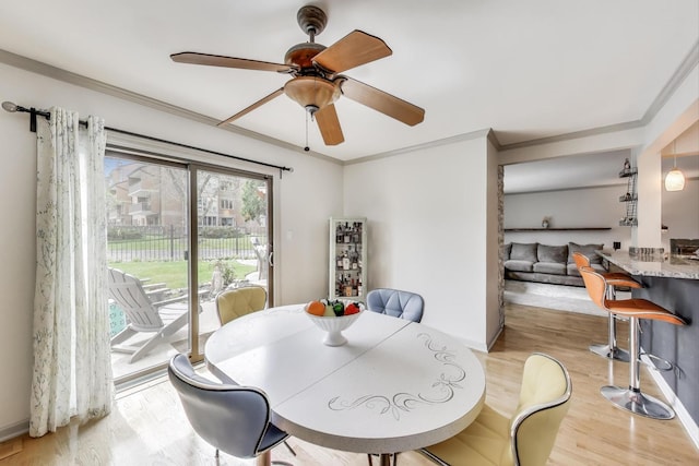 dining area with baseboards, ornamental molding, light wood-style flooring, and a ceiling fan