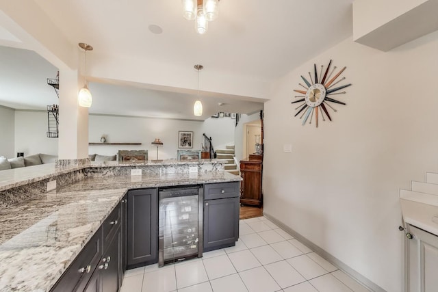 kitchen with light tile patterned flooring, light stone countertops, beverage cooler, open floor plan, and pendant lighting
