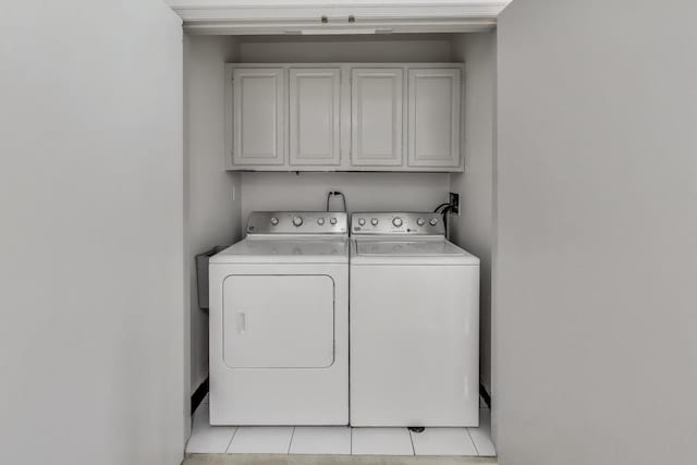 laundry room featuring washer and dryer, light tile patterned flooring, and cabinet space