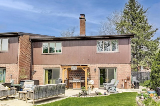 rear view of property featuring fence, a patio, an outdoor hangout area, a chimney, and brick siding