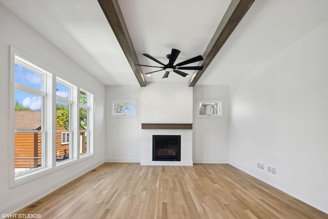 unfurnished living room with beam ceiling, baseboards, a glass covered fireplace, light wood-style floors, and ceiling fan