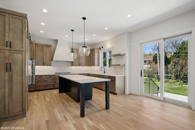 kitchen with a center island, backsplash, custom range hood, open shelves, and light countertops