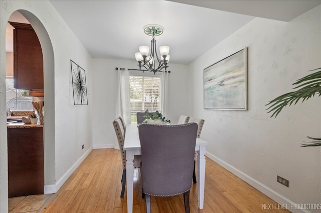 dining space featuring baseboards, a chandelier, and light wood-style floors
