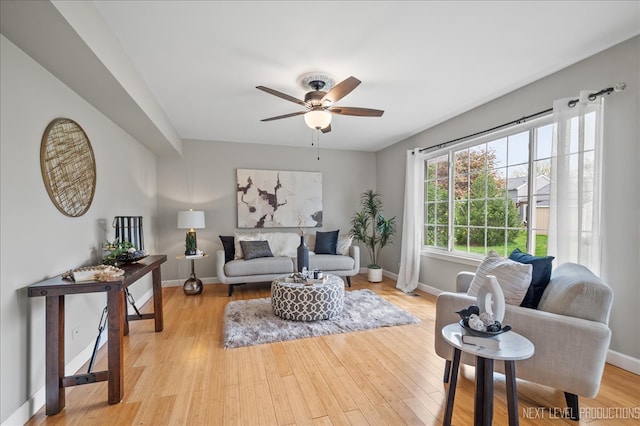 living room with baseboards, ceiling fan, and light wood finished floors
