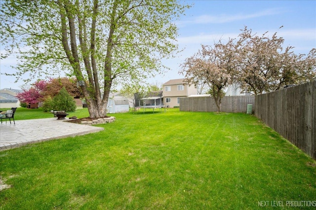 view of yard with a fenced backyard, a trampoline, and a patio area