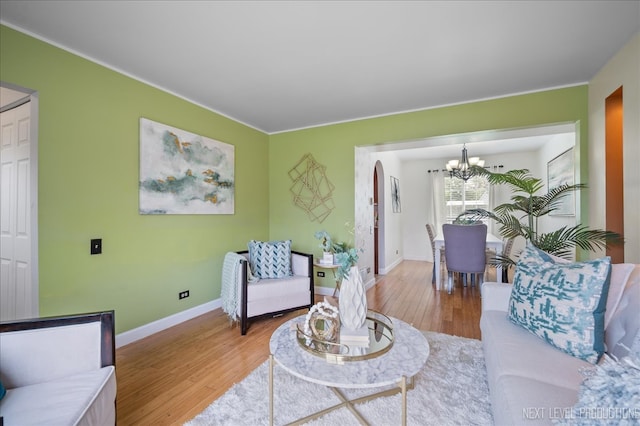 living room with light wood-type flooring, baseboards, crown molding, and a chandelier
