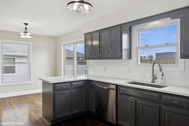 kitchen featuring a sink, decorative backsplash, dishwasher, baseboards, and a peninsula