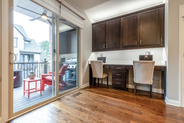 office with built in desk, wood finished floors, a ceiling fan, and baseboards