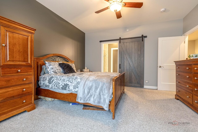 bedroom featuring a barn door, vaulted ceiling, light colored carpet, and ceiling fan