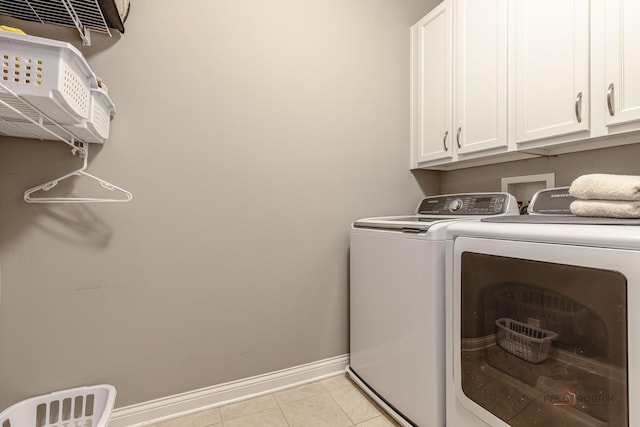 laundry room with baseboards, light tile patterned flooring, washer and clothes dryer, and cabinet space