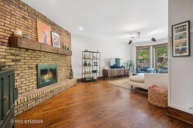 living area featuring baseboards, wood finished floors, and a fireplace