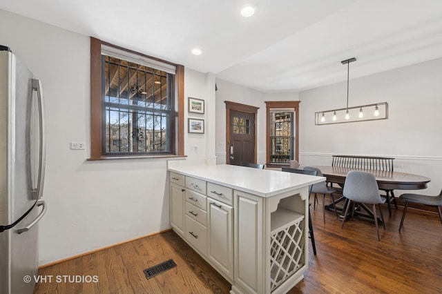 kitchen with visible vents, light countertops, freestanding refrigerator, a peninsula, and dark wood-type flooring