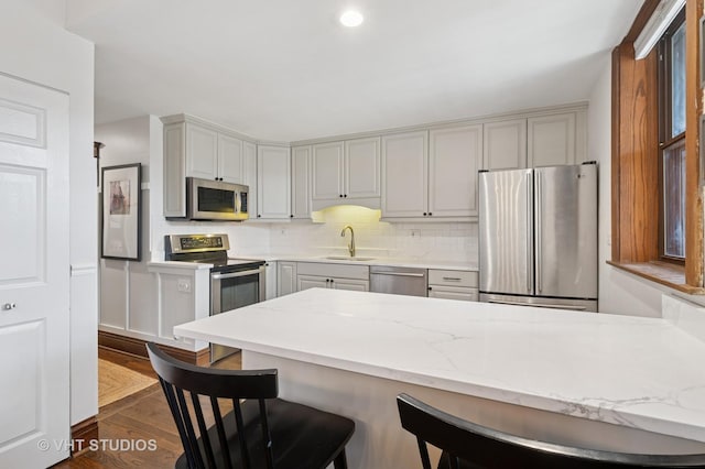 kitchen featuring a peninsula, a breakfast bar area, dark wood-style floors, a sink, and stainless steel appliances