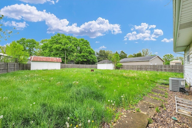 view of yard featuring central air condition unit, a shed, fence, and an outdoor structure
