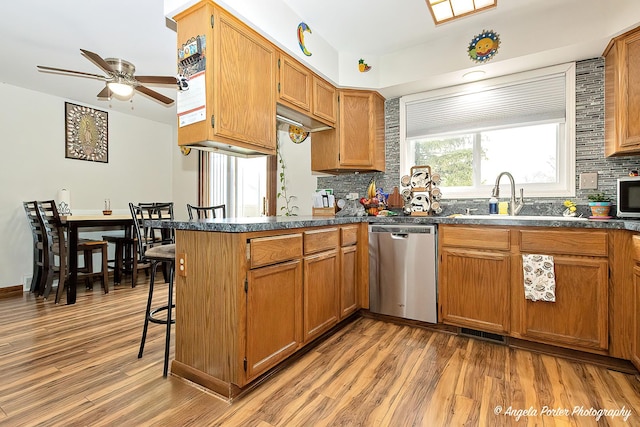 kitchen featuring a peninsula, a sink, dark countertops, stainless steel appliances, and tasteful backsplash