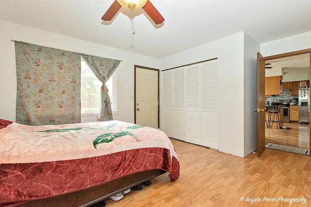 bedroom featuring light wood finished floors, stainless steel fridge with ice dispenser, a ceiling fan, and a closet