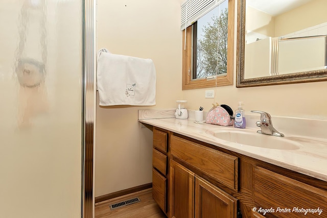 bathroom with a stall shower, vanity, and visible vents
