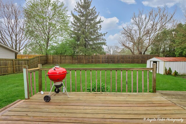 wooden deck featuring a yard, an outbuilding, and a fenced backyard