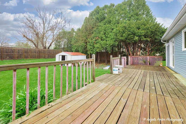 wooden deck featuring a lawn, an outdoor structure, a shed, and a fenced backyard