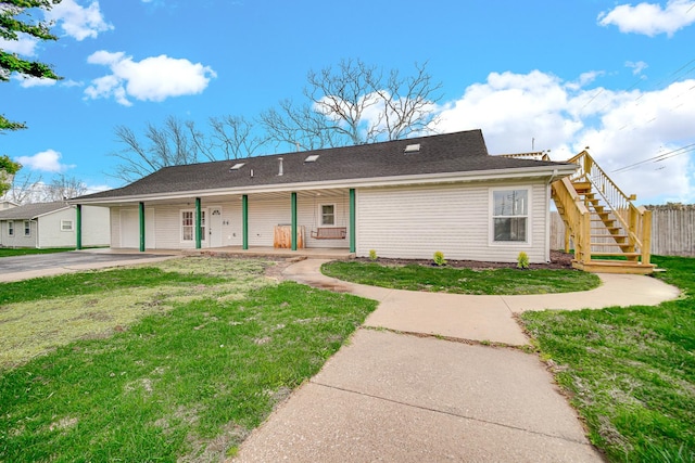 ranch-style home featuring concrete driveway, a front lawn, fence, a porch, and stairs