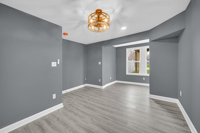 empty room with baseboards, wood finished floors, and recessed lighting