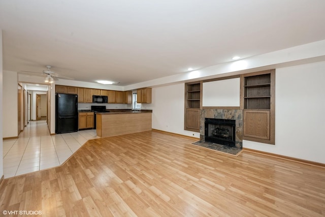 unfurnished living room featuring baseboards, light wood-style floors, a fireplace, recessed lighting, and built in features