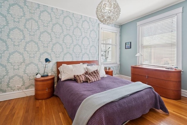 bedroom with an inviting chandelier, hardwood / wood-style flooring, baseboards, and wallpapered walls