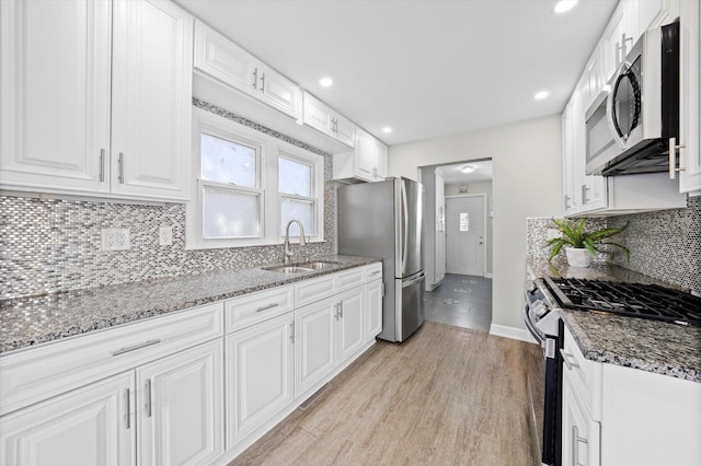 kitchen featuring white cabinets, stone countertops, appliances with stainless steel finishes, and a sink